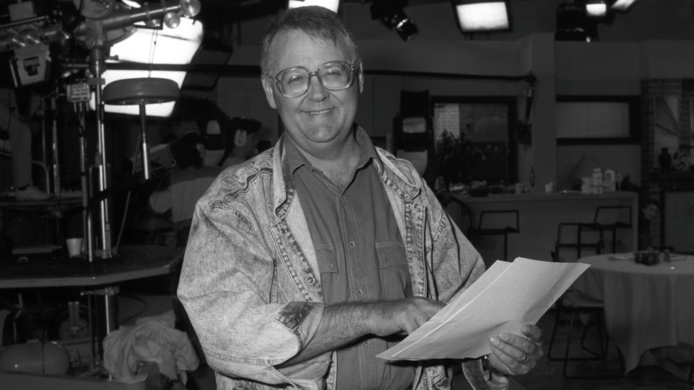 Ian Smith, as Harold Bishop, smiling while holding a script in 1988