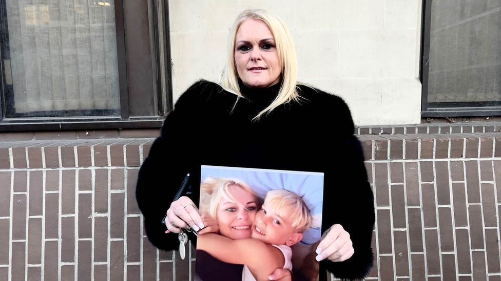 Hollie Dance outside court holding a picture of her with son Archie