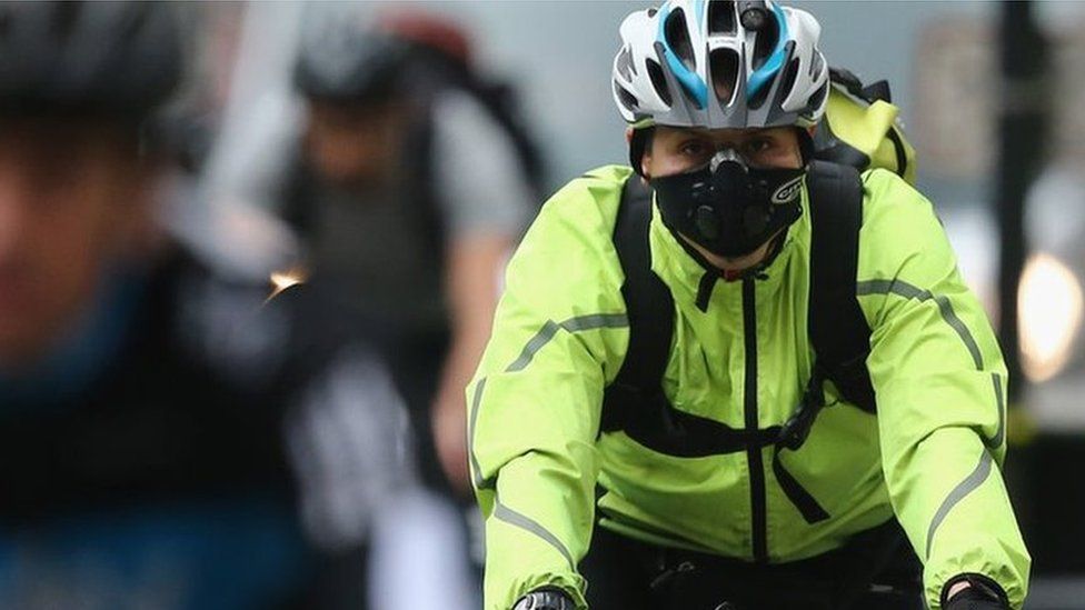 A woman wearing a face mask cycles through Westminster