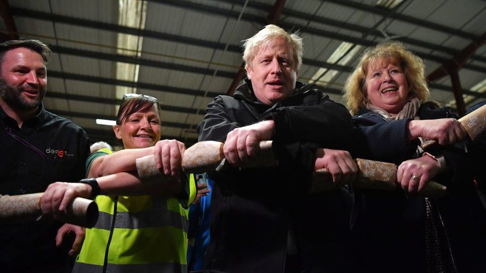 Boris Johnson pulling Christmas crackers with factory staff