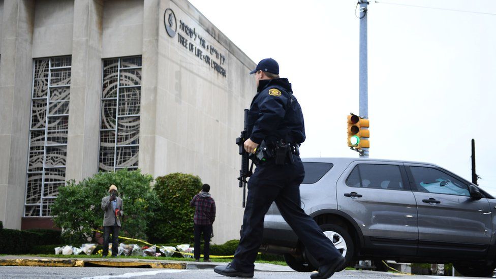 An American police officer crosses the street outside the Tree of Life Synagogue, where 11 people were killed by a right-wing extremist.