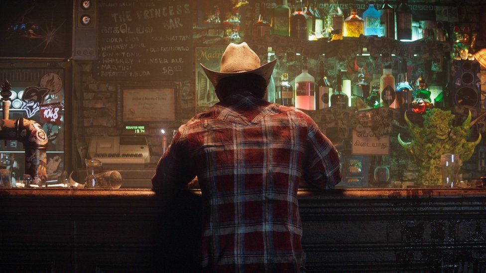 A computer-generated image of a man standing against a bar with his back to the viewer. He's wearing a red and white checked shirt and a cowboy hat. Behind the bar, bottles containing different coloured spirits stuff two shelves, bathed in a neon light. A blackboard has the words