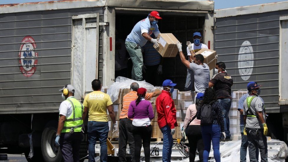 Workers load trucks with boxes of humanitarian aid from China at Caracas airport, 28 March