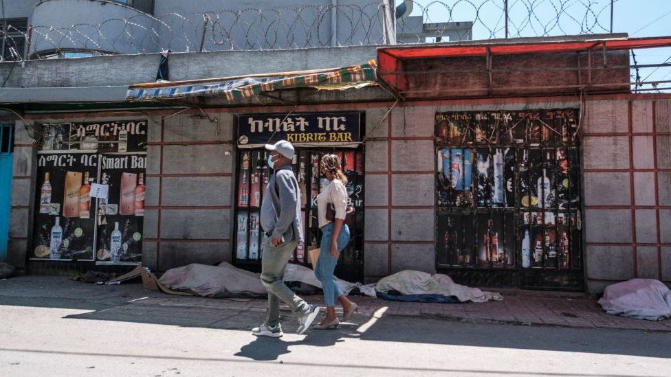 People walk in front of closed shops, in the city of Addis Ababa, Ethiopia, on October 21, 2021