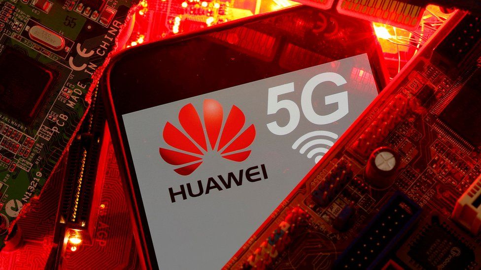The Huawei and 5G logos are seen amid a pile of glowing red printed circuit boards (PCBs)