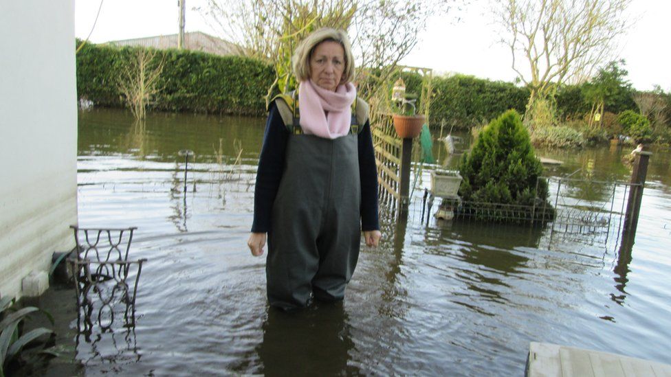 Women stood in overalls with water knee-deep high