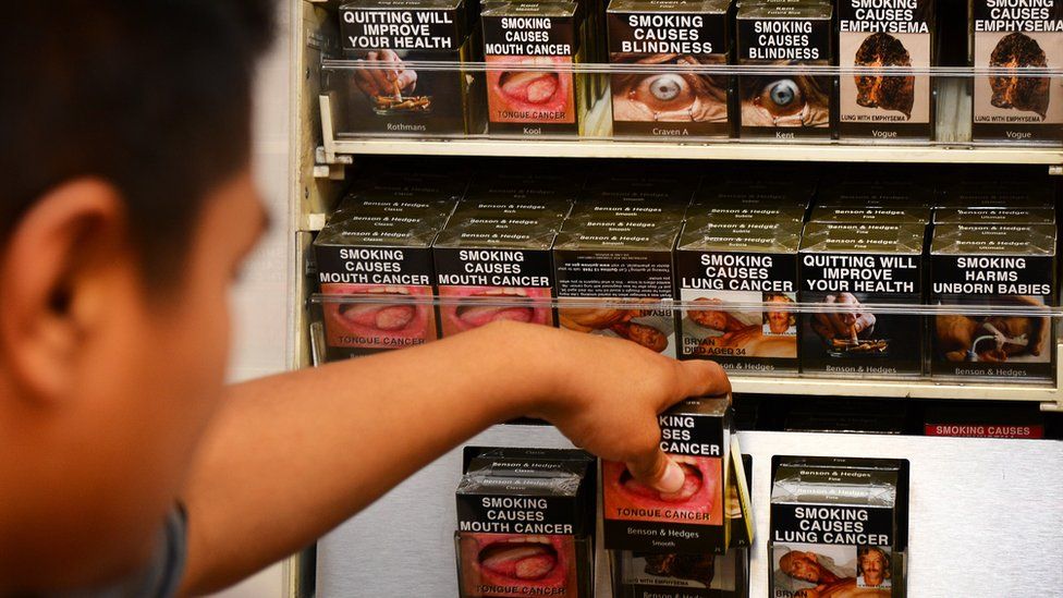 File photograph from 2012 showing an employee in a Sydney shop adjusting cigarette packages bearing some of the images that could be used in the UK in the event of a "no-deal" Brexit.