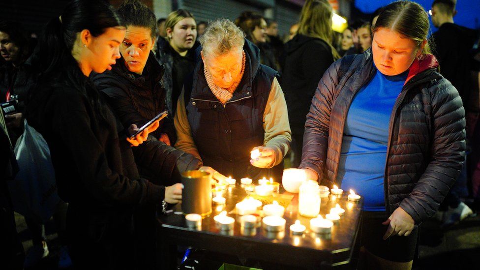 Mourners light candles at a vigil
