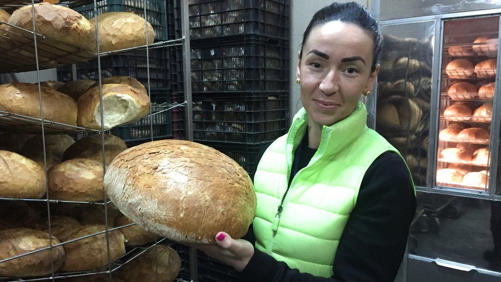 Baker owner Katalin Kollo, holding a big bread roll