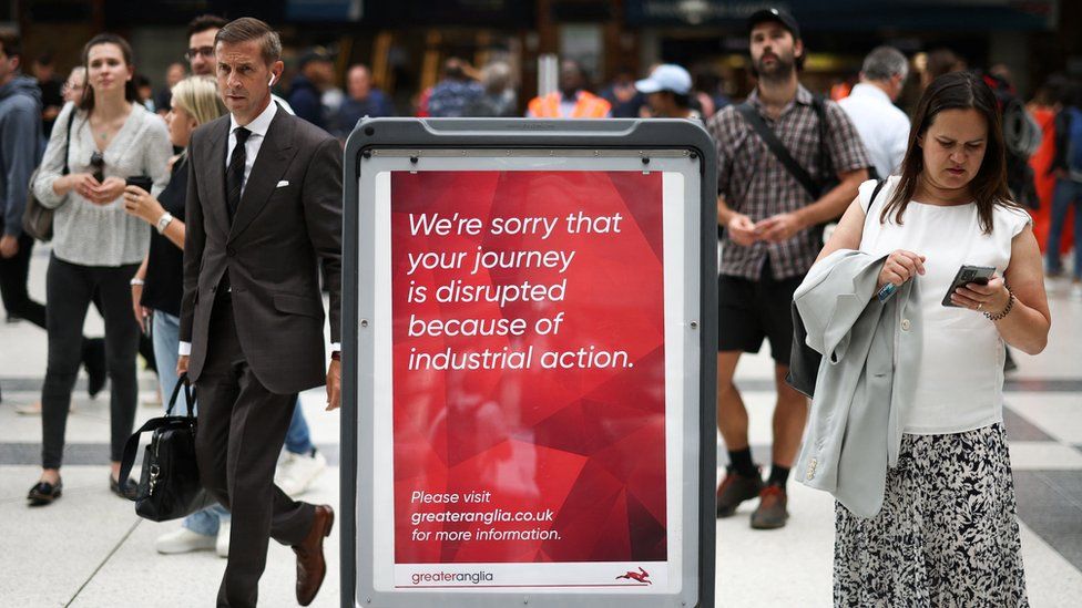 People walk past information signs inside Liverpool Street station in London