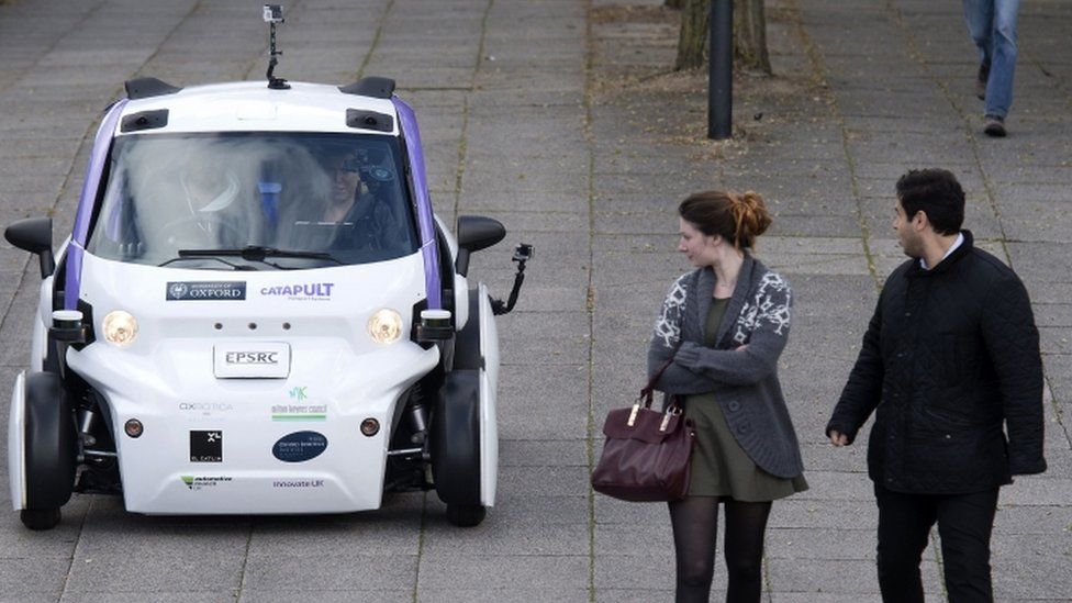 A man and woman look at a self-driving car