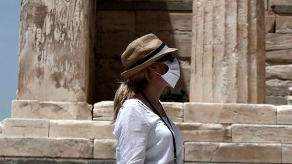 A woman wears a mask at the archaeological site of the Acropolis hill in Athens, 18 May 2020