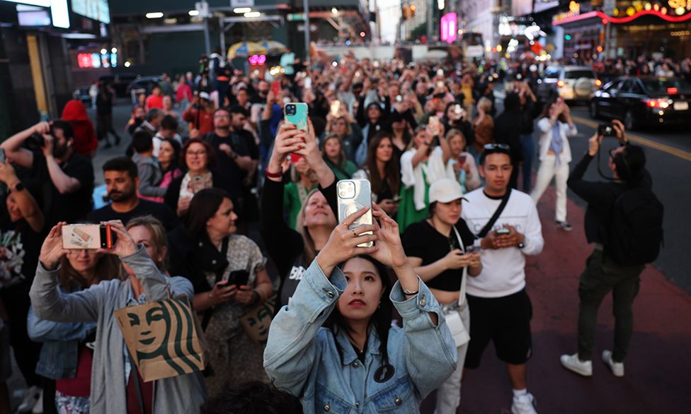 People take photographs of the sunset at 42nd Street in Times Square on one of the four evenings of the year referred to as “Manhattanhenge” when the sun aligns perfectly through spaces between buildings of the New York City street grid on May 30, 2023