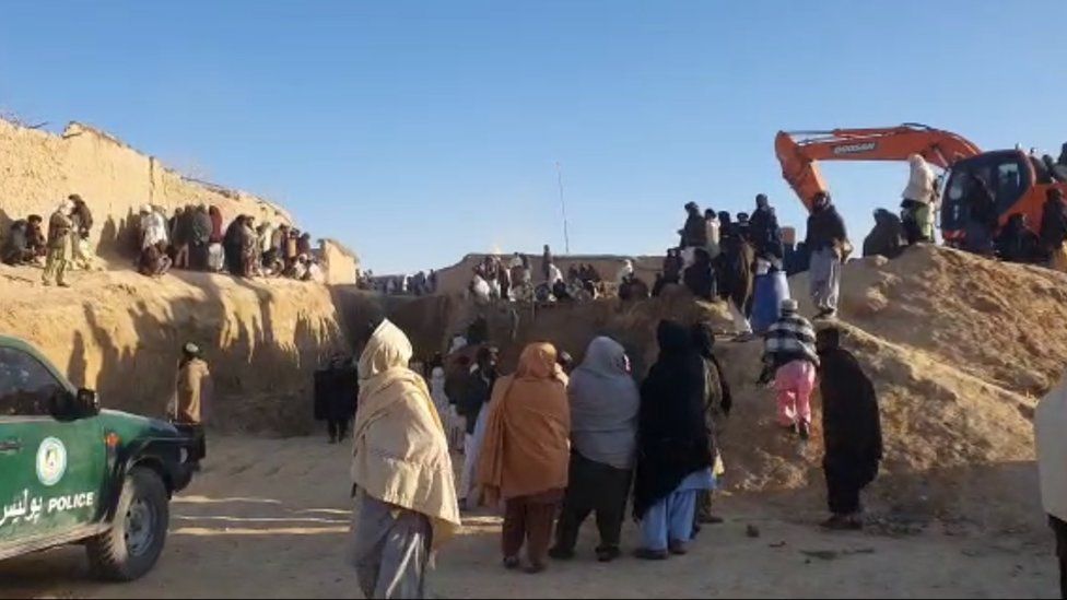 Толпы людей окружают место колодца в Шокак, на юге Афганистана, где стоит кран, чтобы спасти мальчика, застрявшего внутри