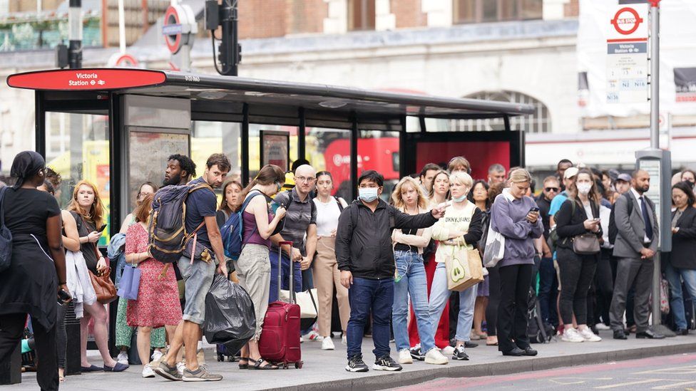 Passengers at a bus stop outside Victoria Station