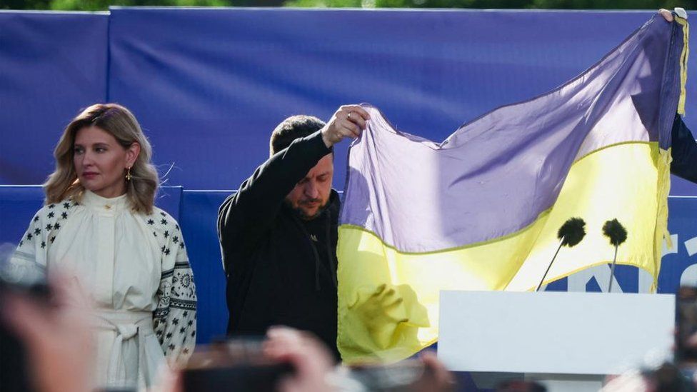 Mr Zelensky holding a Ukrainian flag from the destroyed city of Bakhmut