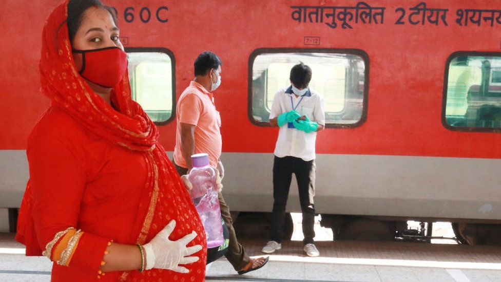Беременная женщина идет к поезду на специальный поезд переменного тока в Нью-Дели после того, как правительство ослабило общенациональную блокировку, введенную в качестве превентивной меры против коронавируса COVID-19 на железнодорожной станции Ховрах в Калькутте 12 мая 2020 года.