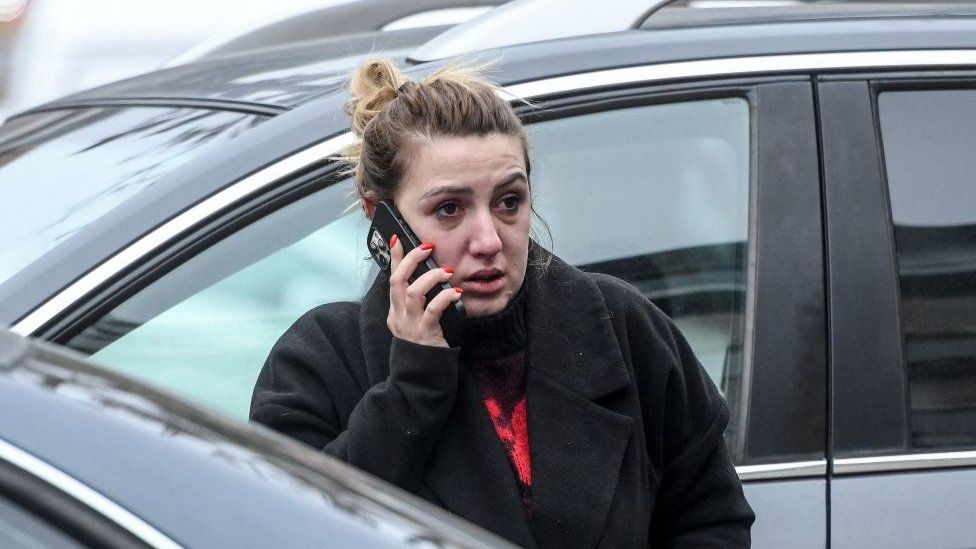 Родственница погибших в автокатастрофе разговаривает по телефону перед офисом туристического агентства Besa Trans