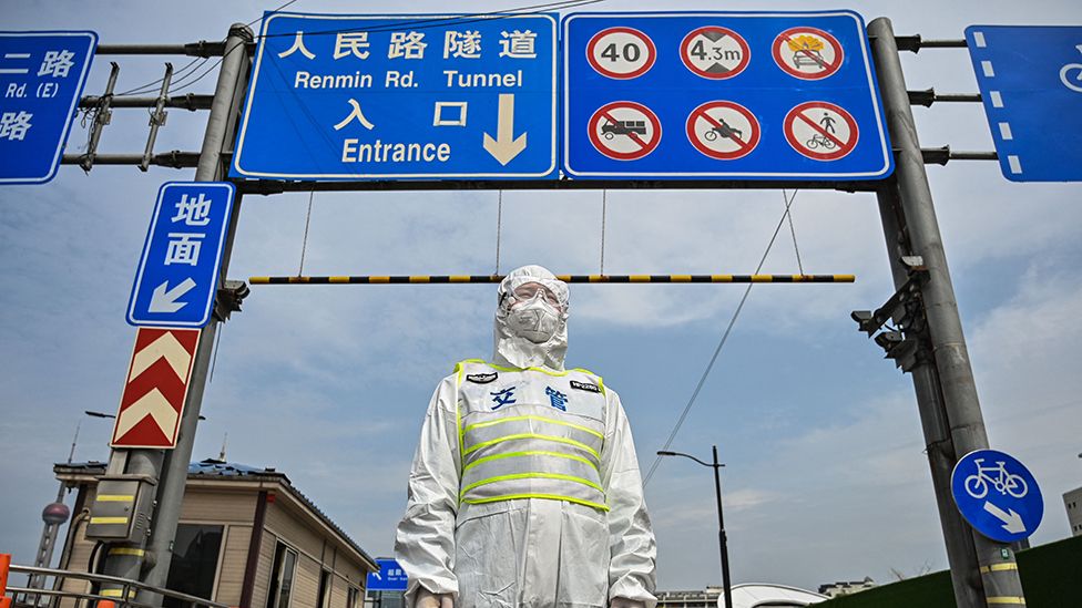 Сотрудник транзитной службы в защитном снаряжении контролирует доступ к туннелю в направлении района Пудун, закрытому в качестве меры против коронавируса Covid-19, в Шанхае, 28 марта 2022 г.