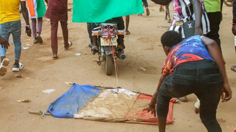 Люди тащат французский флаг на мотоцикле по улицам Ниамея, Нигер. Фото: август 2023 г.