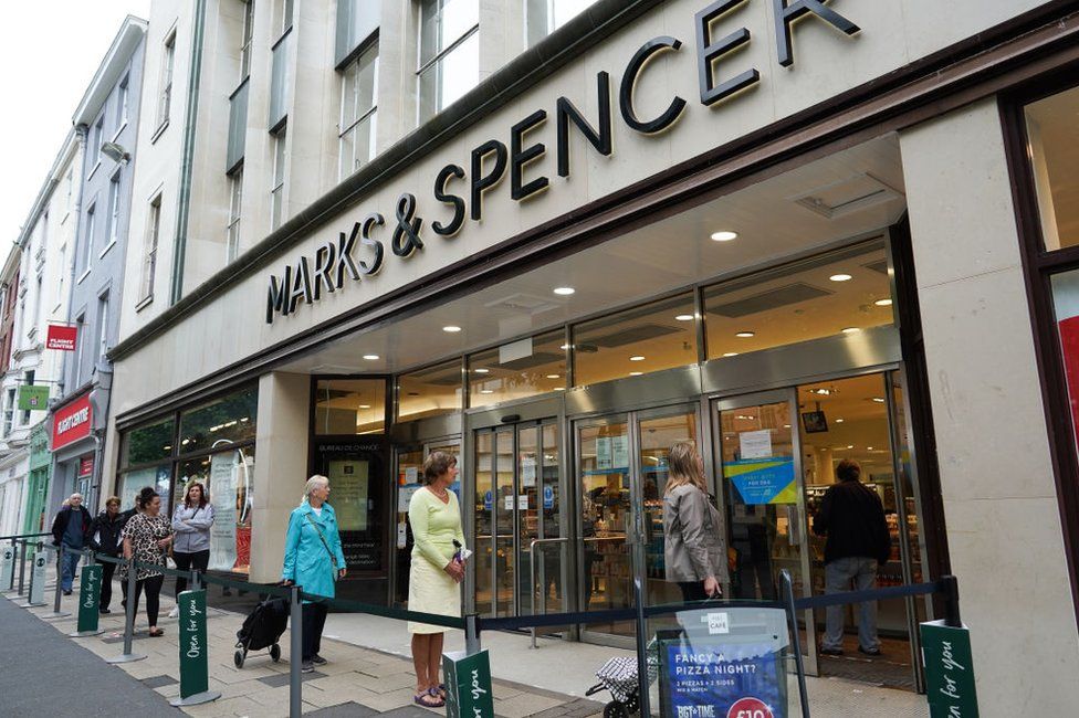 Women stand in a socially distanced queue outside an M&S store