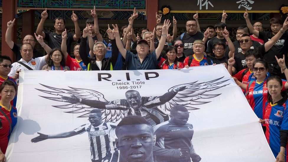 Beijing Enterprises club football fans show a banner that reads 'RIP Cheick Tiote 1986-2017' ahead of a memorial service for Cheick Tiote in Beijing on June 13, 2017.