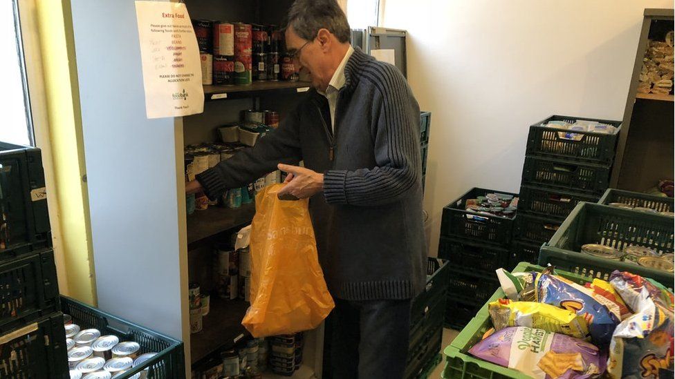 A volunteer filling a bag with food