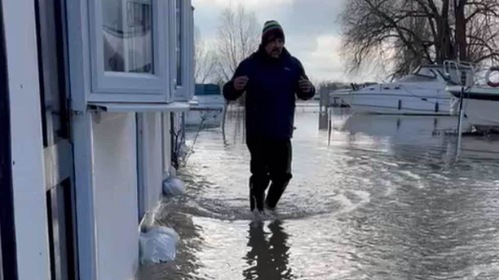 A hotel worker wades through the flood water