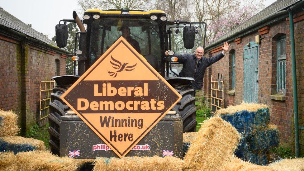 Sir Ed Davey launches the Lib Dem local election campaign by driving a tractor through a pile of hay bales in Berkhamsted