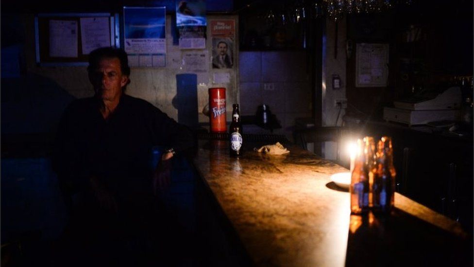 An employee remains at a liquor store during a partial power cut in Caracas on February 6, 2018.