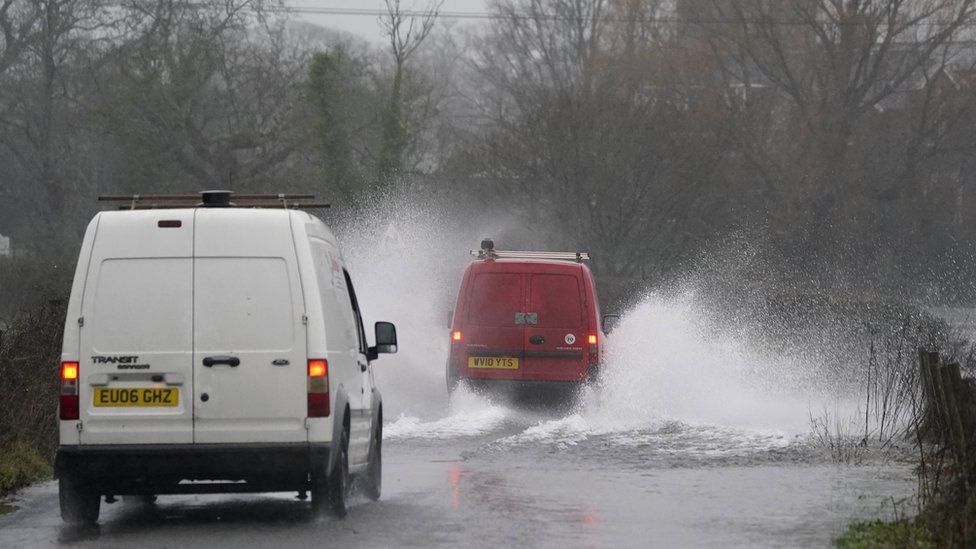 Cars drive through flood water along Kent Lane, near to Ibsley in Hampshire