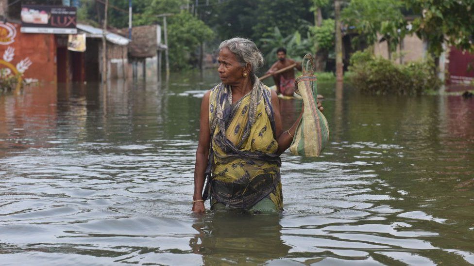 A woman is seen waded through the flooded water. 6th August, 2021, West Bengal