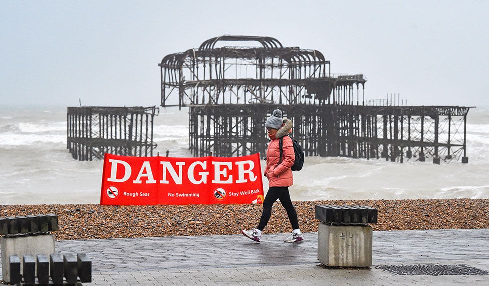 A walker passes by a Danger sign on Brighton on 18 February 2022