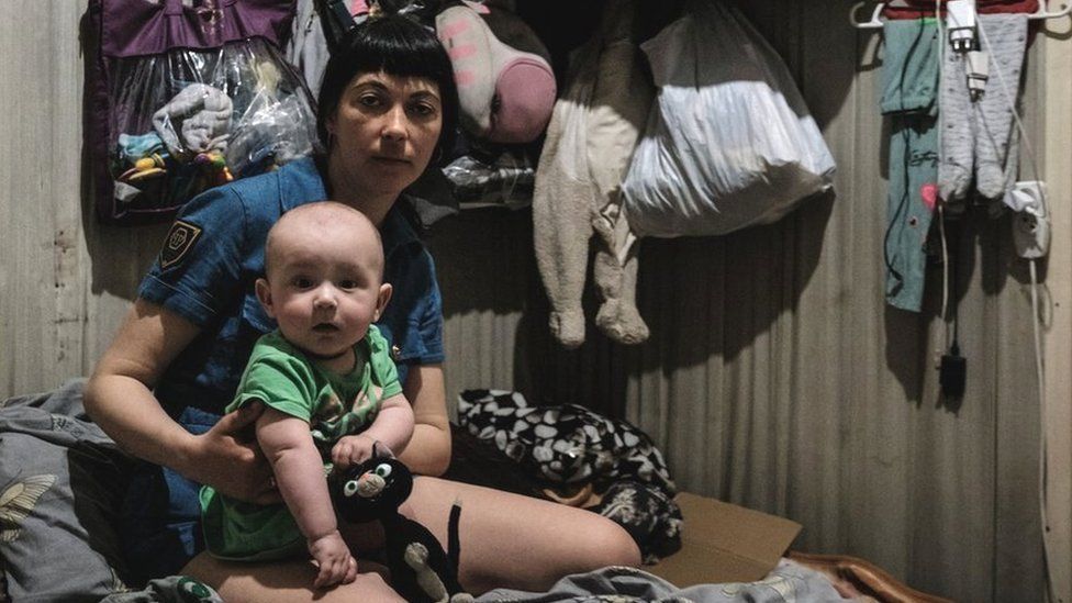 A woman poses with her 7-month-old daughter in the bunker of a factory in Lysychansk