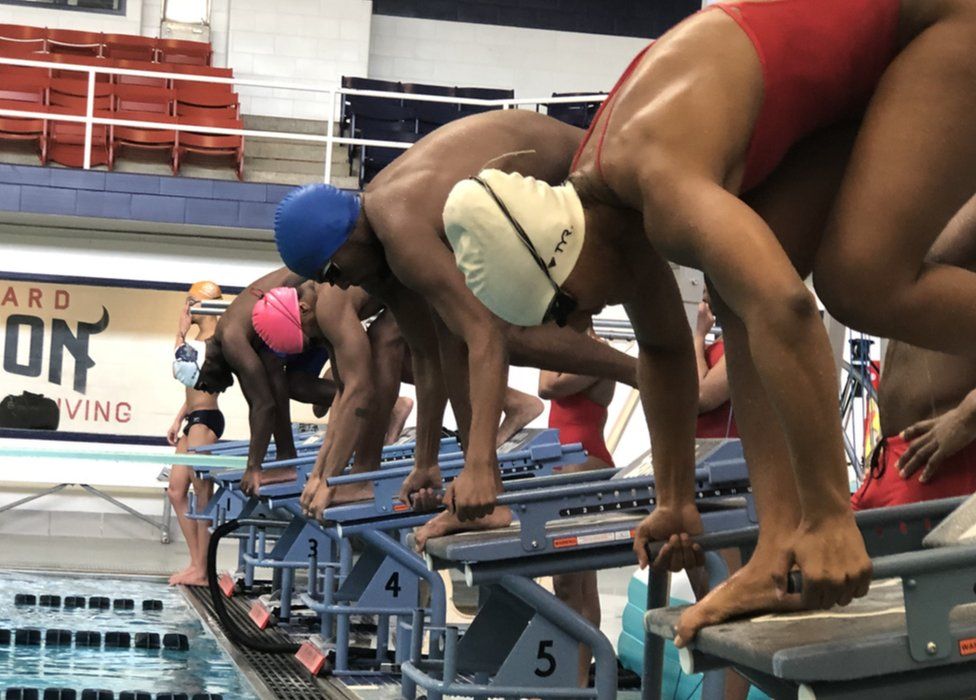 Swimmers diving in to a pool