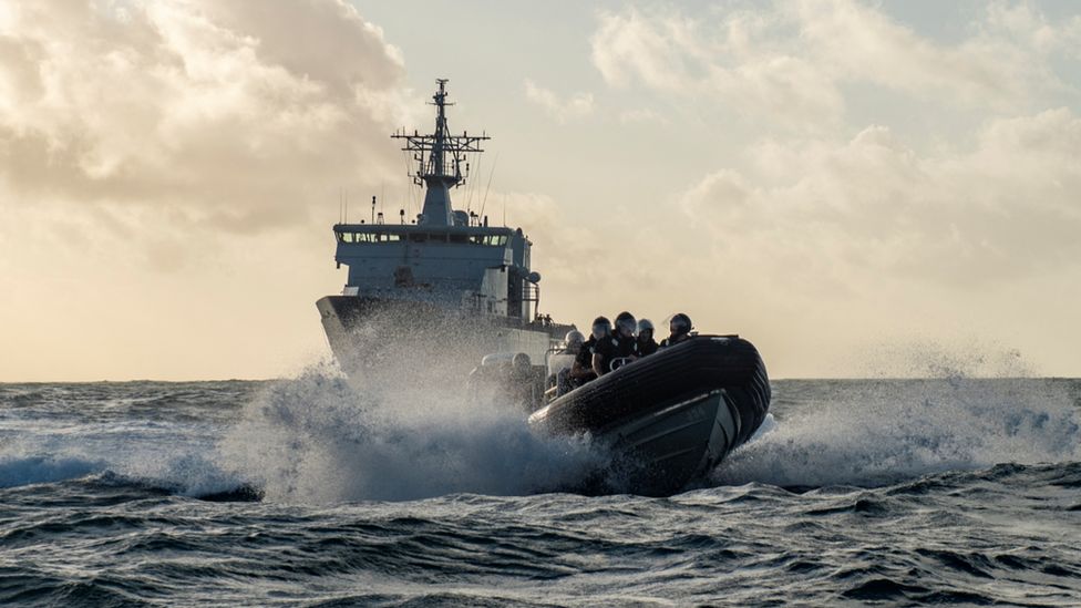 Военно-морской катер Новой Зеландии впереди более крупного корабля по прибытии в Тонгу