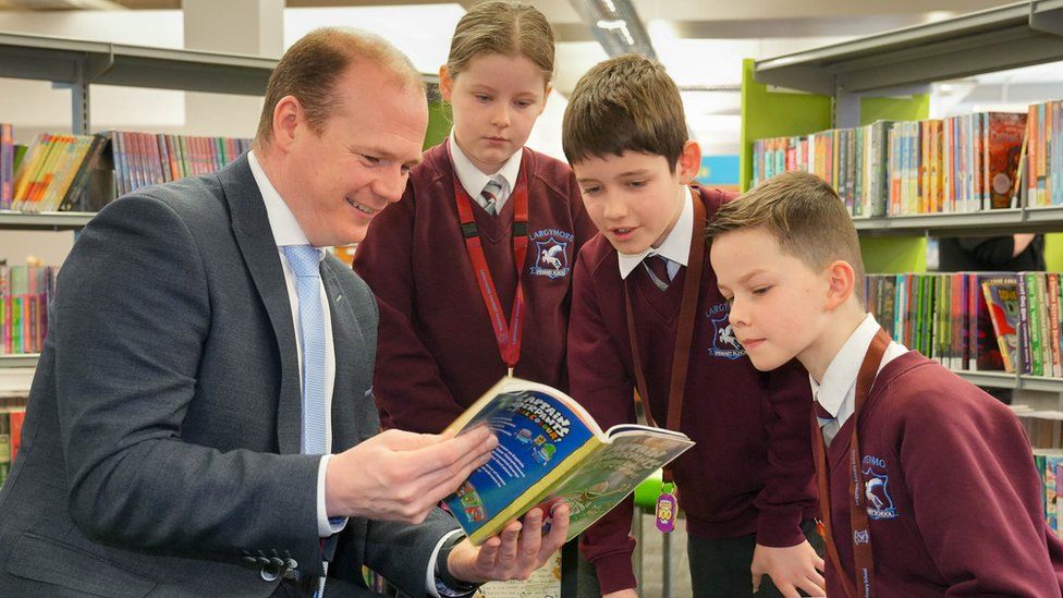 Communities Minister Gordon Lyons with pupils from Largymore Primary School as they celebrate World Book Day at Lisburn Library