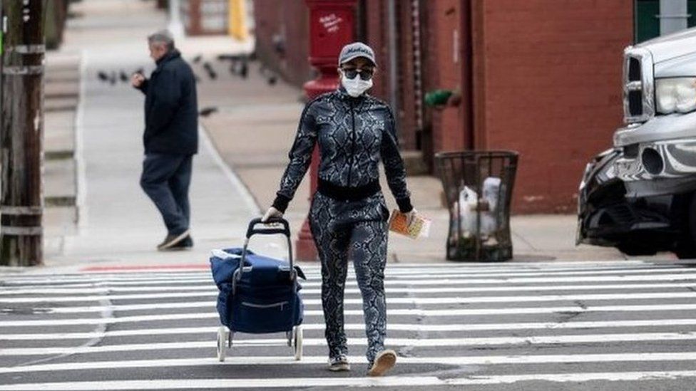 A woman wearing a mask crosses a road in Queens, New York (30/03/20)