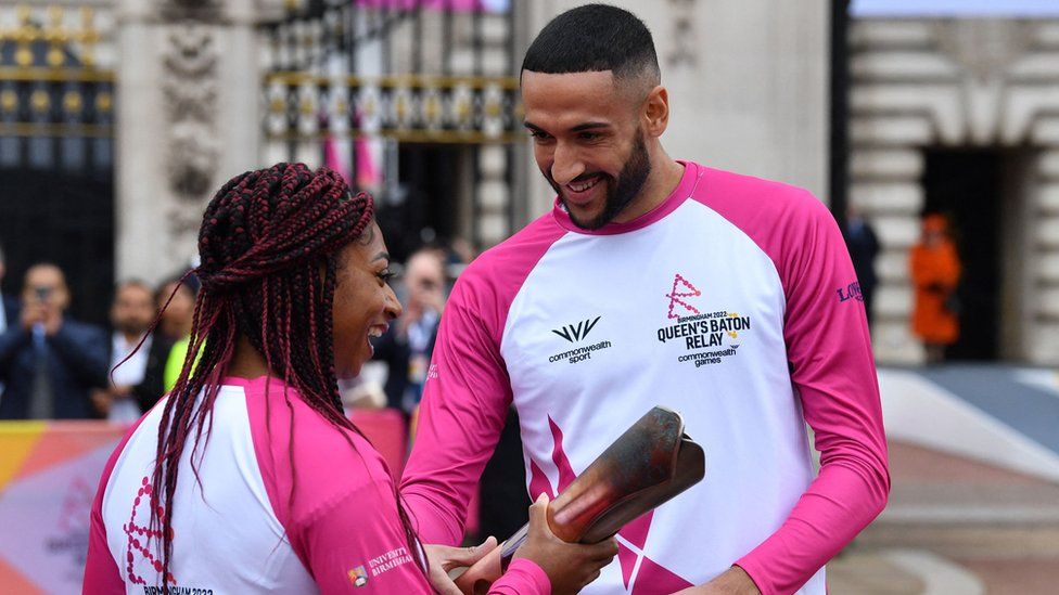 The first Baton-bearer, double Paralympic gold medallist Kadeena Cox (L) hands over the baton to Team England squash player Declan James as Britain's Queen Elizabeth II launches the Queen's Baton Relay for the Birmingham 2022 Commonwealth Games, from the forecourt of Buckingham Palace in London on October 7, 2021