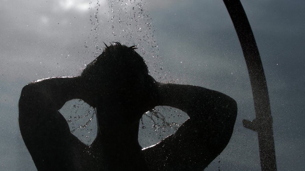 A file photo of a male figure in silhouette taking a shower outdoors