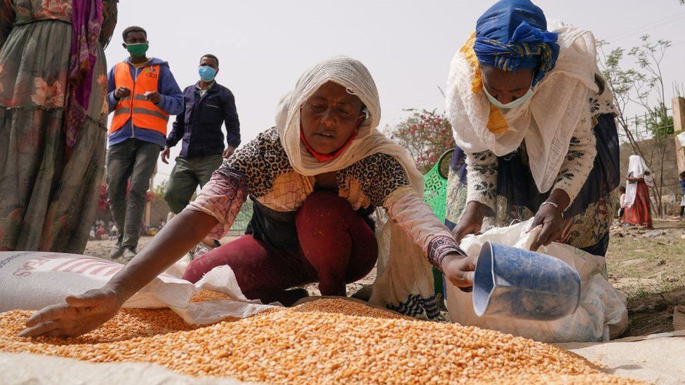 An aid worker distributes measured portions of yellow lentils to residents of Geha subcity at an aid operation run by USAID, Catholic Relief Services and the Relief Society of Tigray on June 16, 2021 in Mekele, Ethiopia.