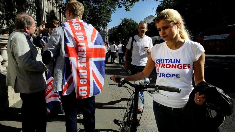 A vote remain supporter walks past a vote leave supporter outside Downing Street