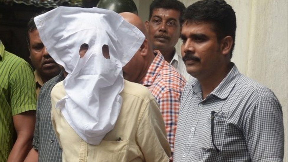 Полицейские сопровождают Санджив Кханна (с закрытым лицом), бывшего мужа Индрани Мукерджа, обвиняемого в убийстве собственной дочери Шины Бора в апреле 2012 года, в суд в Калькутте 27 августа 2015 года