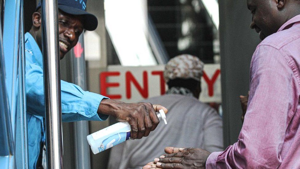 A security guard gives hand disinfectant to visitors as precaution measures at an entrance of building in Nairobi, Kenya - 13 March 2020