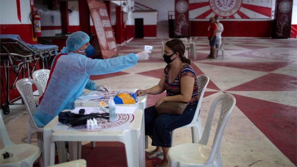 A physician checks the temperature of a woman with symptoms in Rio de Janeiro, Brazil, on 24 May