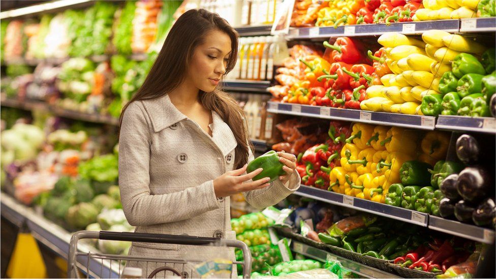 A woman looking at a green pepper