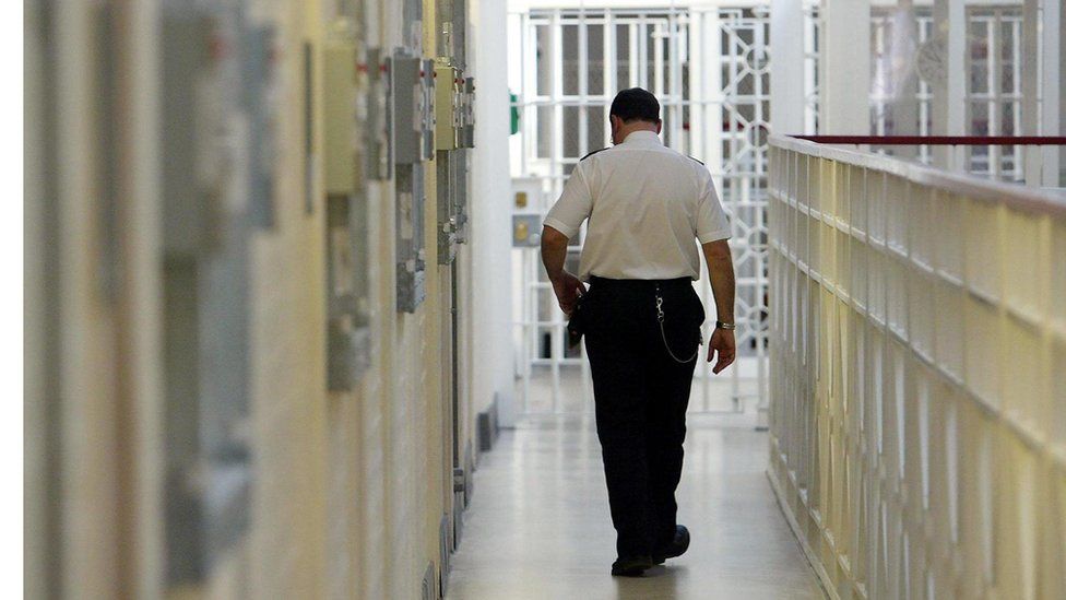 Prison officer walking past jail cells