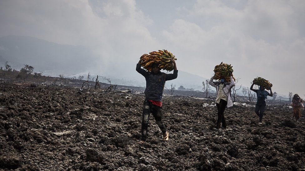 Конголезские общины, идущие по потокам лавы в Кибати, к северу от города Гома, после извержения вулкана в Северном Киву, Демократическая Республика Конго, 25 мая 2021 г.