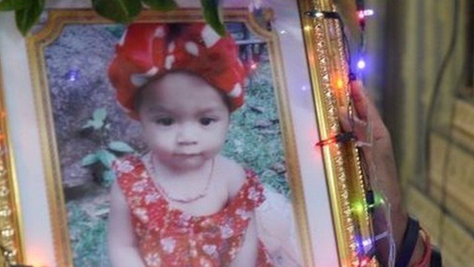 Jiranuch Trirat, mother of 11-month-old daughter who was killed by her father who broadcast the murder on Facebook, stands next to a picture of her daughter at a temple in Phuket,