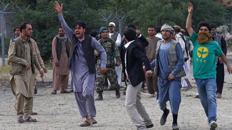 People shout slogans at the scene of three bombings that targeted the funeral of a victim of the violent protests in Kabul